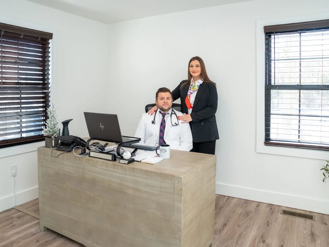 Dr. Kurtovic seated at his desk in the Pleasant Valley office with a member of the practice team