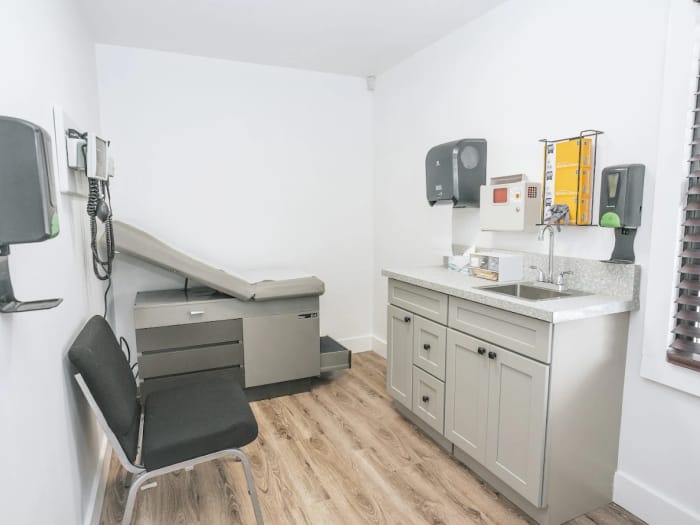An exam room with an exam table, sink and wall-mounted diagnostic equipment
